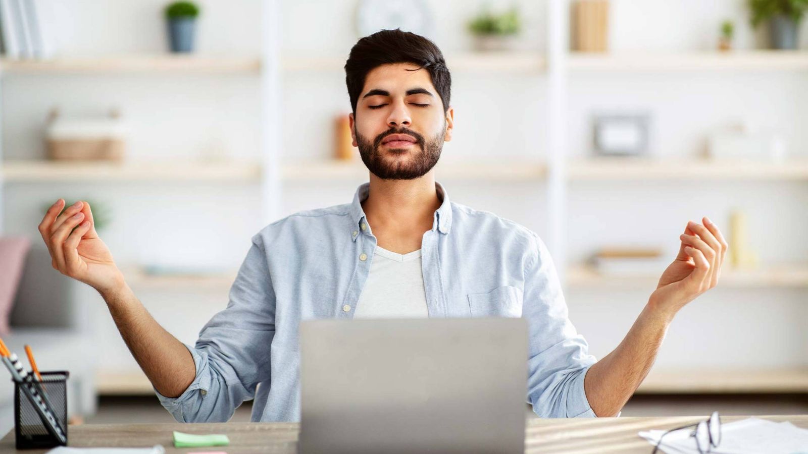 Young Man meditando en la oficina de escritorio contra la computadora portátil concepto de conciencia abierta