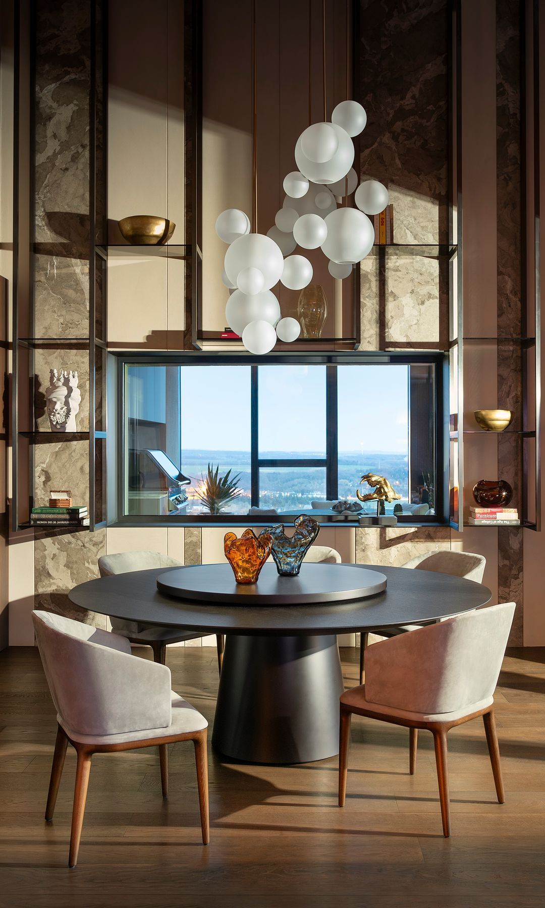 Mesa redonda negra, lámpara de techo con globos blancos, septum de mitad de cristal se comunica con cocina al aire libre