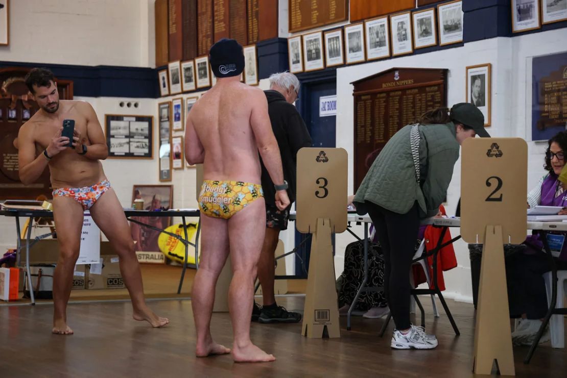 Un hombre toma una foto de un votante complementario mientras se prepara para votar en las elecciones generales en un centro de votación en el Bondi Surf Bathers Life Saving Club en Sydney el sábado.