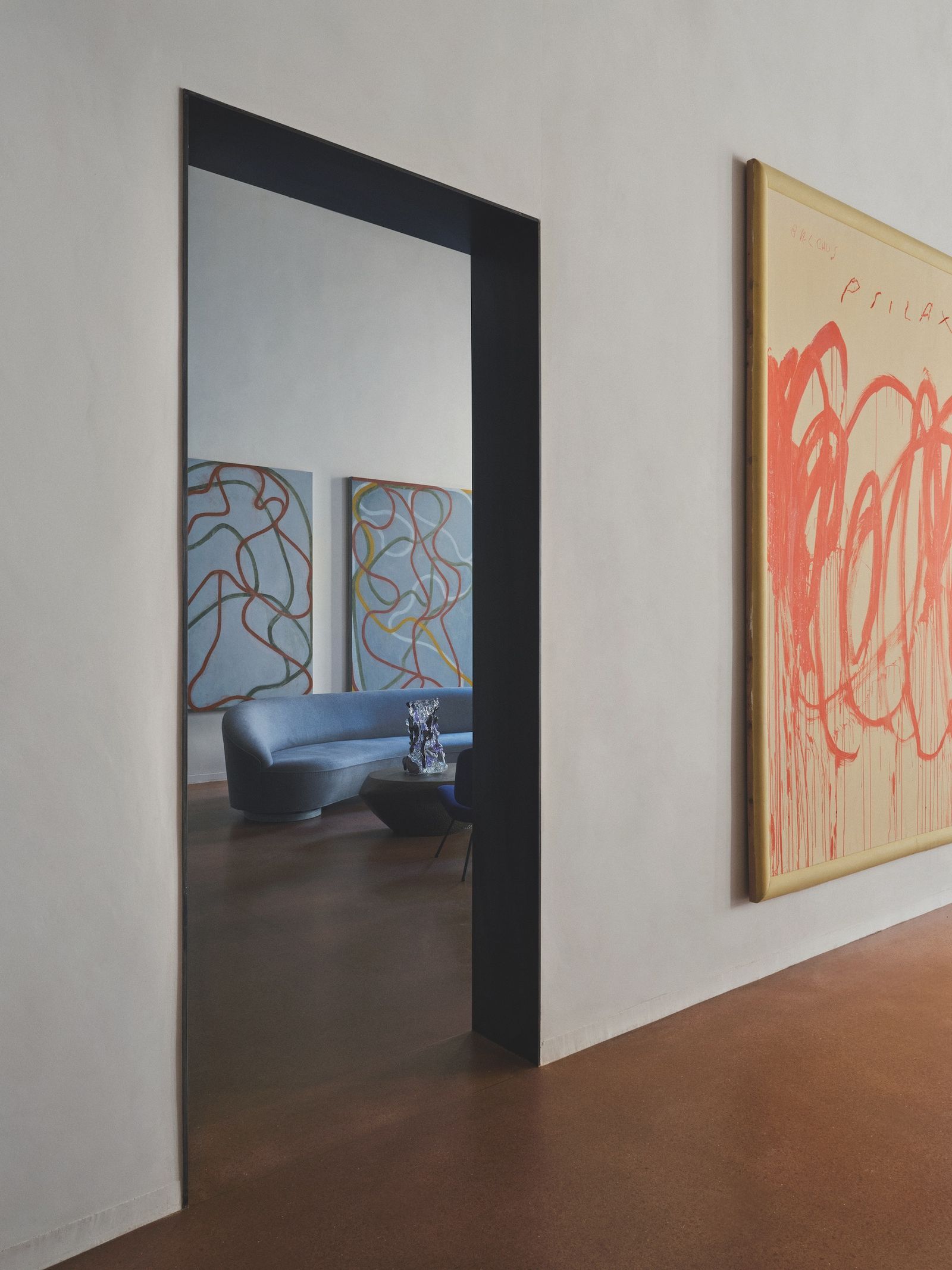 Sala de puertas que le da a otro con un SOF azul y obras de arte
